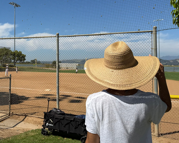 A mom in sun hat at youth baseball game
