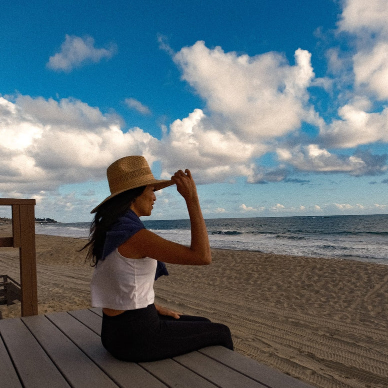 Stylish woman at the beach wearing UPF 50+ sun hat to protect from the harmful sun